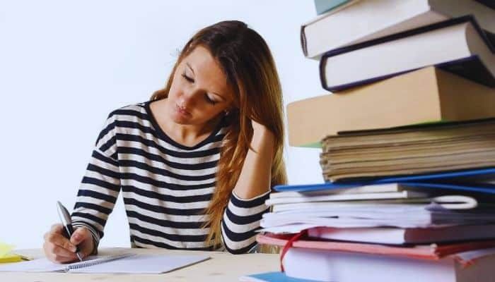 A person sitting at a desk with a stack of books